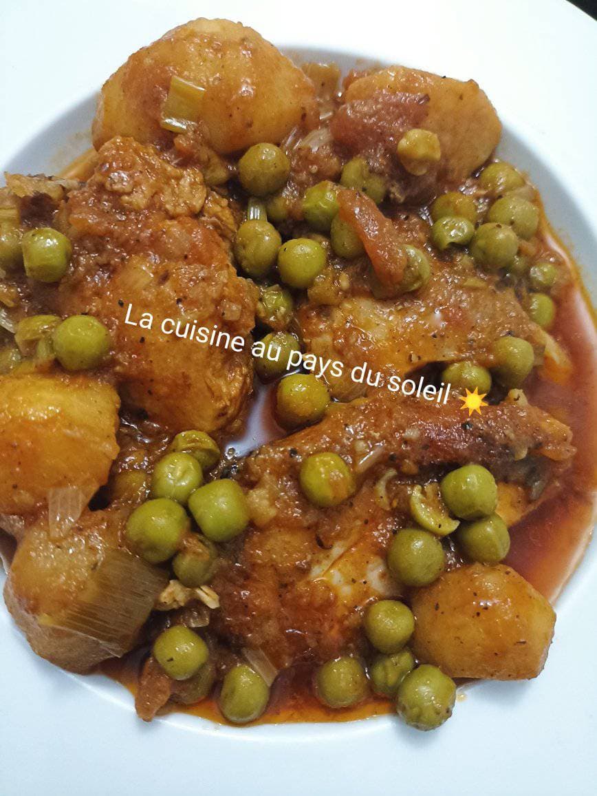 Poulet à la sauce tomate avec des petits pois et des pommes de terre.