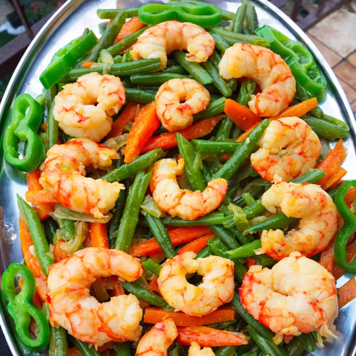 Entrée chaude aux crevettes sautées à l’ail, haricots verts et carottes.