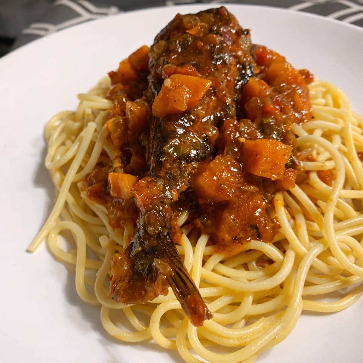Maquereau dans la sauce tomate accompagné de spaghettis .